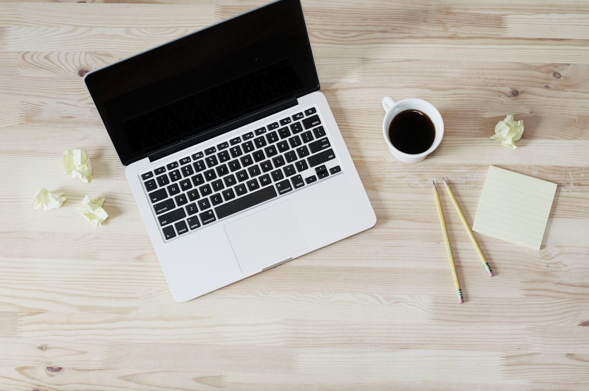 Laptop aperto e tazza di caffè su scrivania in legno, pronti per una consulenza online