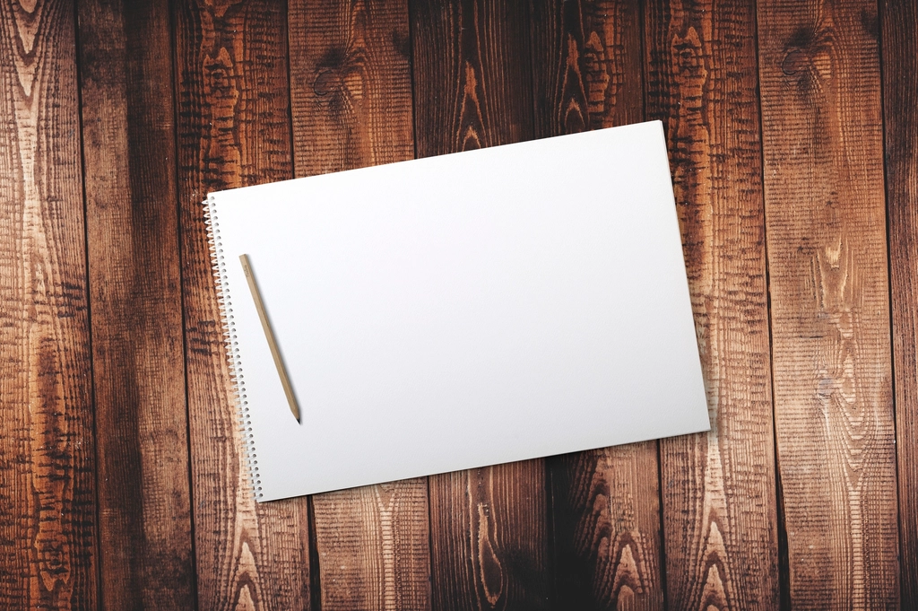 Quaderno bianco e matita su tavolo di legno
